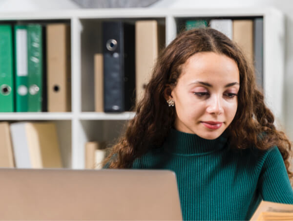 Woman working on laptop in office setting.