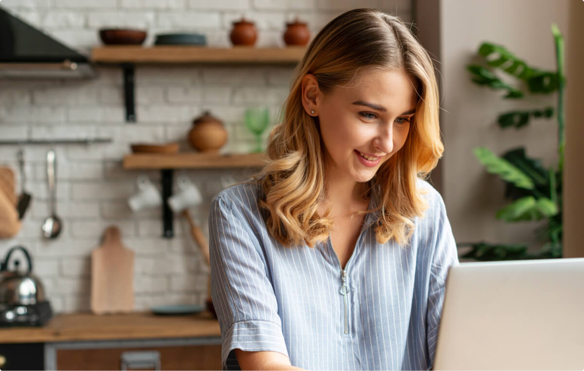 Woman smiling using laptop in modern kitchen