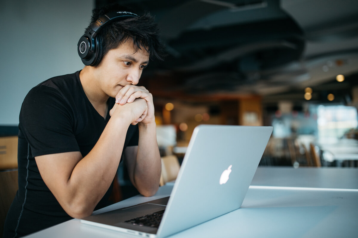 Person wearing headphones using a laptop in cafe.