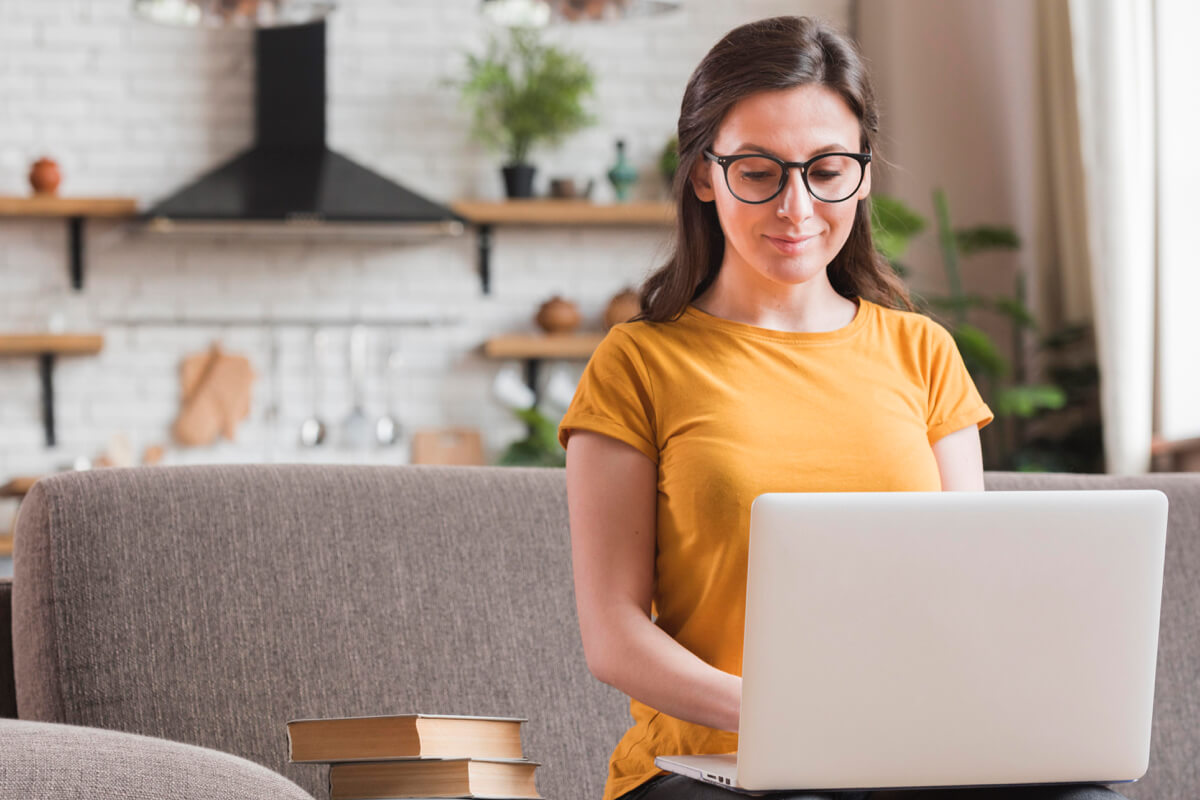 Woman in glasses using laptop on sofa