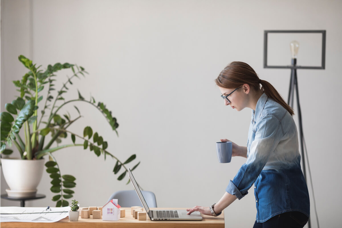 Woman drinking coffee at laptop workspace