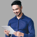 Smiling man using a tablet in blue shirt.
