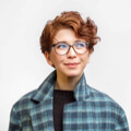 Person with glasses wearing plaid coat looks upward.